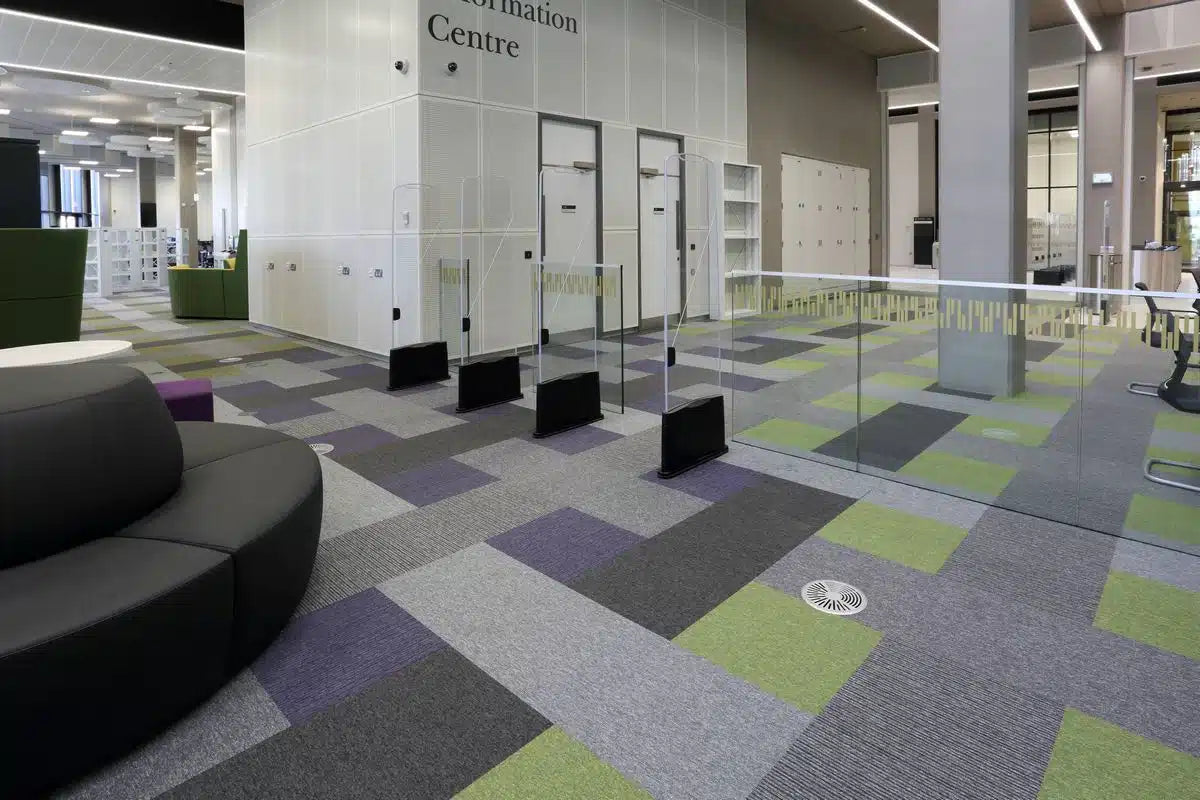 Tivoli® carpet tiles in a university library information centre, in green, purple and grey - installation example for Tivoli® Carpet Tiles in Palm Green