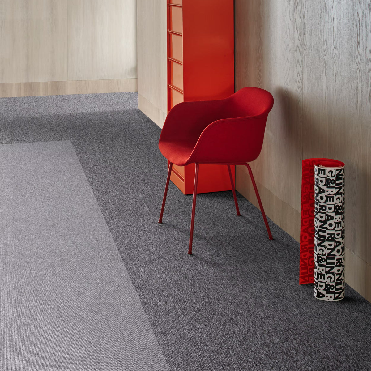 Interface Employ Loop carpet tiles in Gritstone and Ash with a red chair
