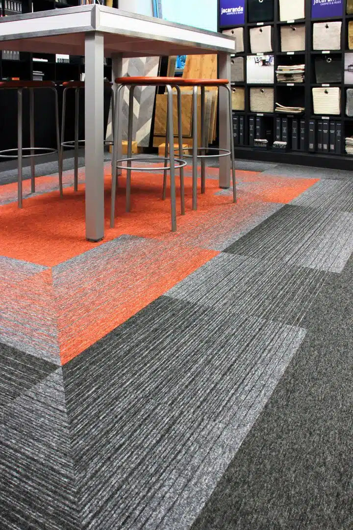 Burmatex Tivoli Mist carpet tiles in orange and grey displayed in a carpet showroom