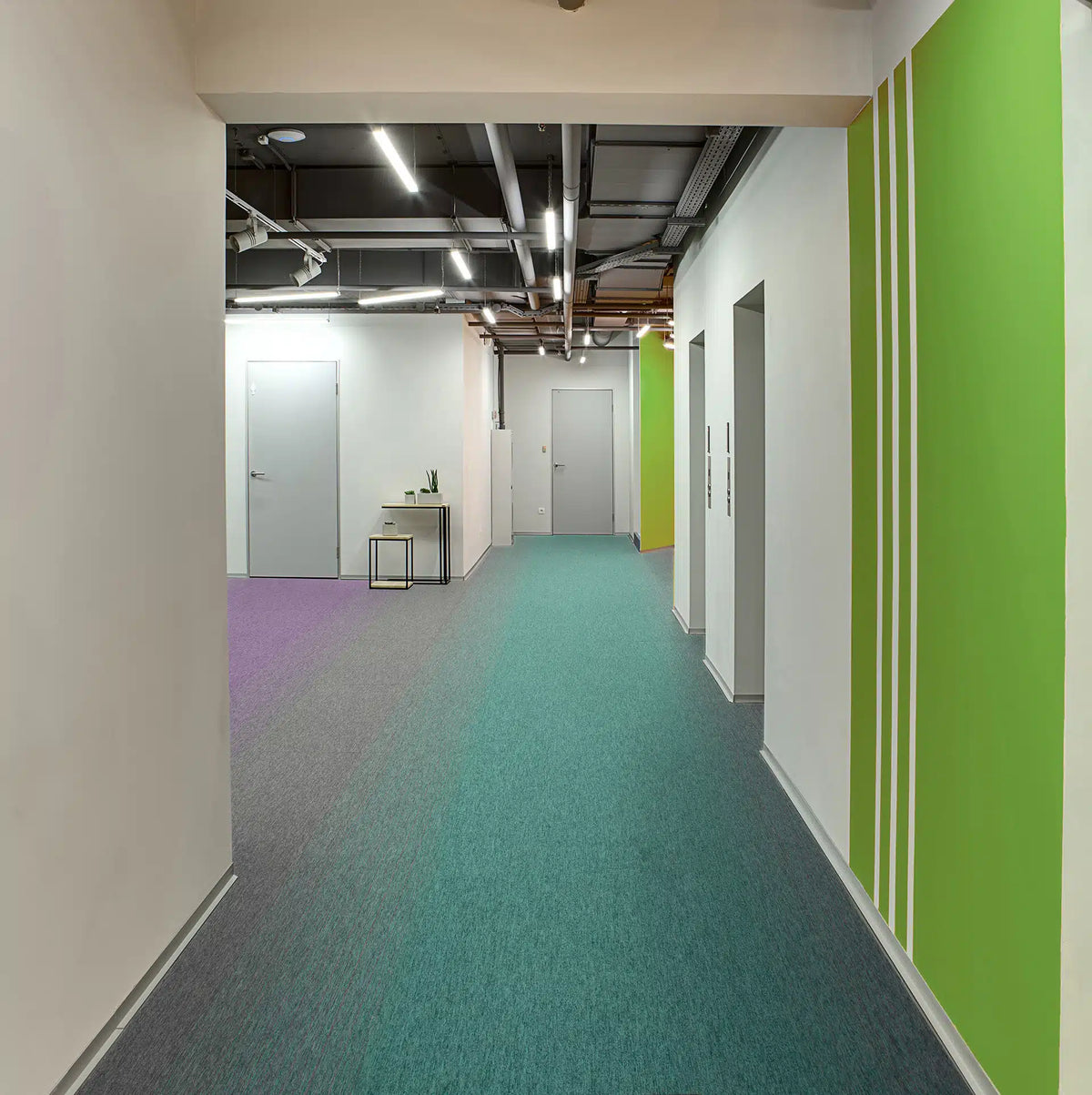 Burmatex Tivoli Mist carpet tiles in teal, grey and purple running through an office corridor
